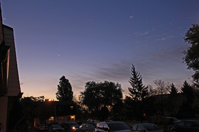 Cirrus clouds point towards a tiny crescent moon, 