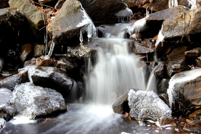 Ice froming on rocks beside waterfall 