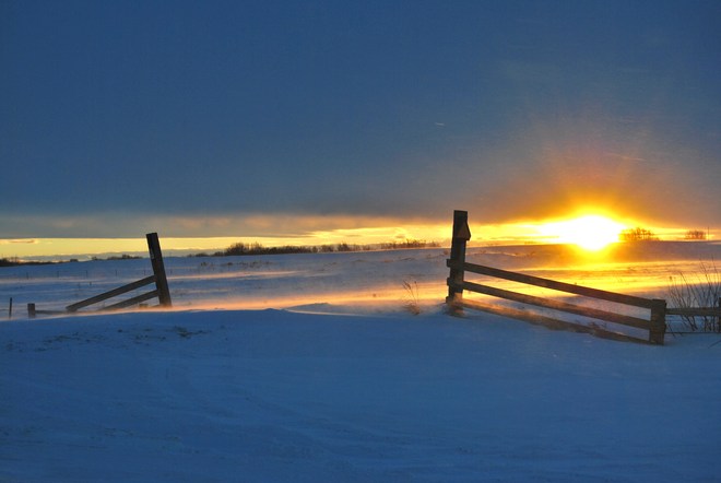 sunset on fence and blowing snow Unity, Saskatchewan Canada