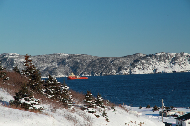 Ship escorting oil rig out to sea as seen from the beach hill on Bell Island Bell Island, Newfoundland and Labrador Canada