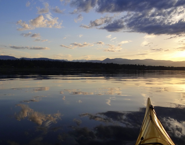 A peaceful nights paddle in the Comox Bay with cloud reflections and a setting s Royston, BC, Canada